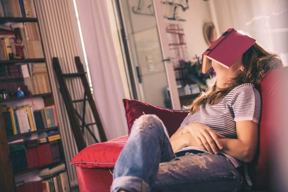 Frau auf Couch mit Buch auf dem Gesicht