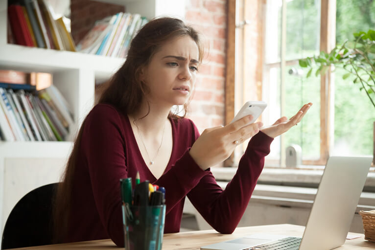 Eine Frau sieht verwundert auf ihr Telefon