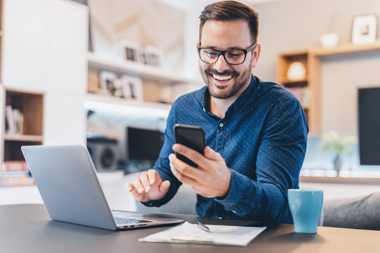 Ein lächelnder Mann gibt seinen Lotto-Tipp online ab, während er aus dem Home-Office arbeitet